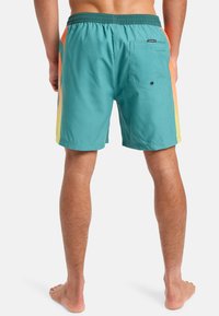 Tyrkysové plavky s oranžovými a žlutými gradientními bočními panely, elastický pas a zadní kapsa se zapínáním na knoflík.