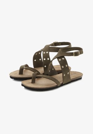 Sandales en daim vert olive avec des brides entrecroisées, petits clous et une semelle en liège plate. Comprend une sangle réglable à la cheville et une boucle pour les orteils.