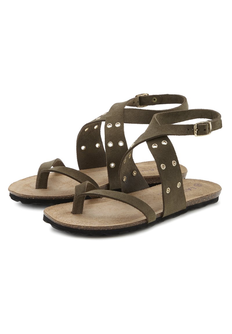 Olivgrüne Wildledersandalen mit überkreuzten Riemen, kleinen Nieten und einer flachen Korksohle. Mit verstellbarem Knöchelriemen und Zehenring.