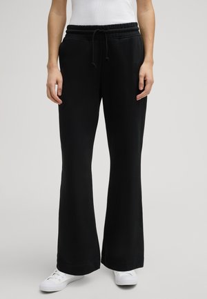 Pantalons de survêtement noirs évasés avec une taille élastique et un cordon de serrage, en tissu doux ; dotés de poches latérales et d'un logo discret sur la hanche.