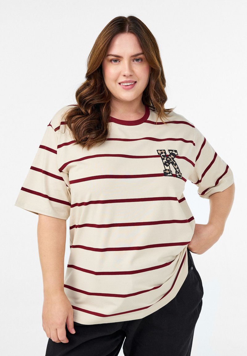 Beige striped t-shirt features maroon horizontal lines, a crew neckline, and a leopard-patterned pocket accent. Fabric appears soft and relaxed.