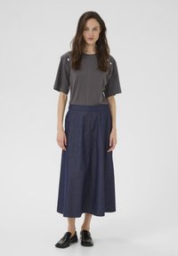 Top gri cu mânecă scurtă, cu accente la umeri, asortat cu o fustă A-line din denim închis și pantofi slip-on negri. Design simplu și modern.