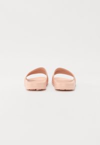Rosa gummislippers med to brede stropper og en strukturert fotseng. Flat såle med små spor for bedre grep.