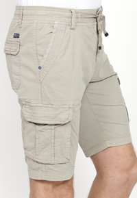 Helle beige Cargo-Shorts mit mehreren Taschen, verstellbarem Kordelzugbund und gesteppten Details für zusätzliche Textur.