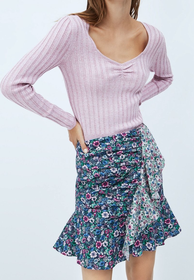 Light pink ribbed long-sleeve top with a scoop neckline paired with a floral-patterned wrap skirt featuring ruffled hem and multiple colors.