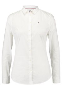 Camisa blanca de botones confeccionada en algodón, con un cuello clásico, mangas largas y un pequeño logo bordado en el lado izquierdo del pecho.