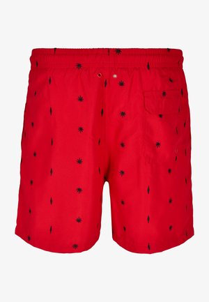 Červené plavkové šortky s čiernymi listovými vzormi, elastickým pásom s šnúrkou a jednou zadnou vreckom. Hladká textúra látky.