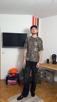 Kortärmad skjorta med kamouflagemönster i olika gröna nyanser, kombinerad med lösa svarta byxor med intrikat broderi. Svarta skor fulländar outfiten.