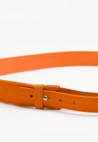 Pomarańczowy skórzany pasek o gładkiej teksturze, z klamrą i kilkoma otworami do regulacji. Czysty, minimalistyczny design.