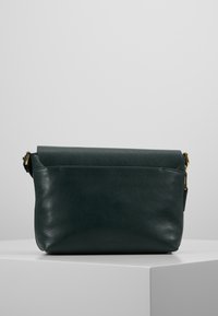 Borsa a tracolla verde in pelle con superficie texturizzata e chiusura superiore arrotolata. Presenta hardware in tono oro e una tasca posteriore con zip.