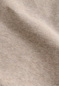 Strukturiert brauner Stoff mit weichem, gewebtem Aussehen, der ein dezentes Melange-Muster zeigt. Die Oberfläche ist glatt und leicht aufgeraut.