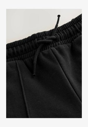 Crne pamučne trenirke s elastičnim pojasom, podesivim šniranjem i dva bočna džepa. Glatka tekstura i jednostavan dizajn.