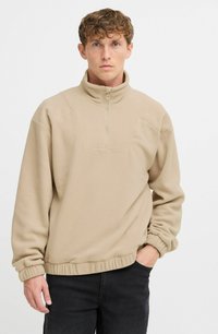Beige fleece pullover med halvdækkende lynlås krave, elastisk søm og manchetter; har et mønstret forpanel og en afslappet pasform.