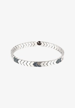 Bracelet couleur argent avec des maillons interconnectés en forme de chevrons et un petit fermoir magnétique rond noir, isolé sur fond blanc.