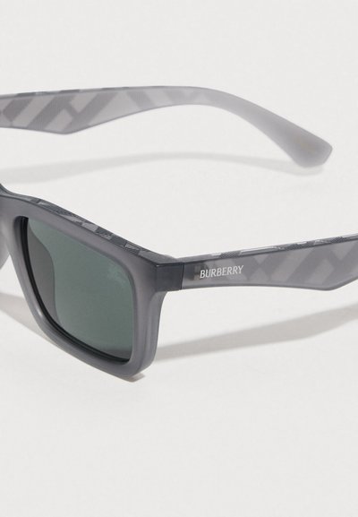 Γυαλιά ηλίου Burberry με γκρι πλαστικό σκελετό, σκουρό πράσινους φακούς και διακοσμητικές γκρι λεπτομέρειες στους βραχίονες. Κομψός, γωνιώδης σχεδιασμός.