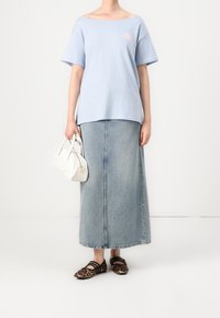 Světle modré volné tričko, džíny maxi sukně, bílá kabelka a ploché boty s leopardím potiskem. Jednoduchý design a ležérní textury.