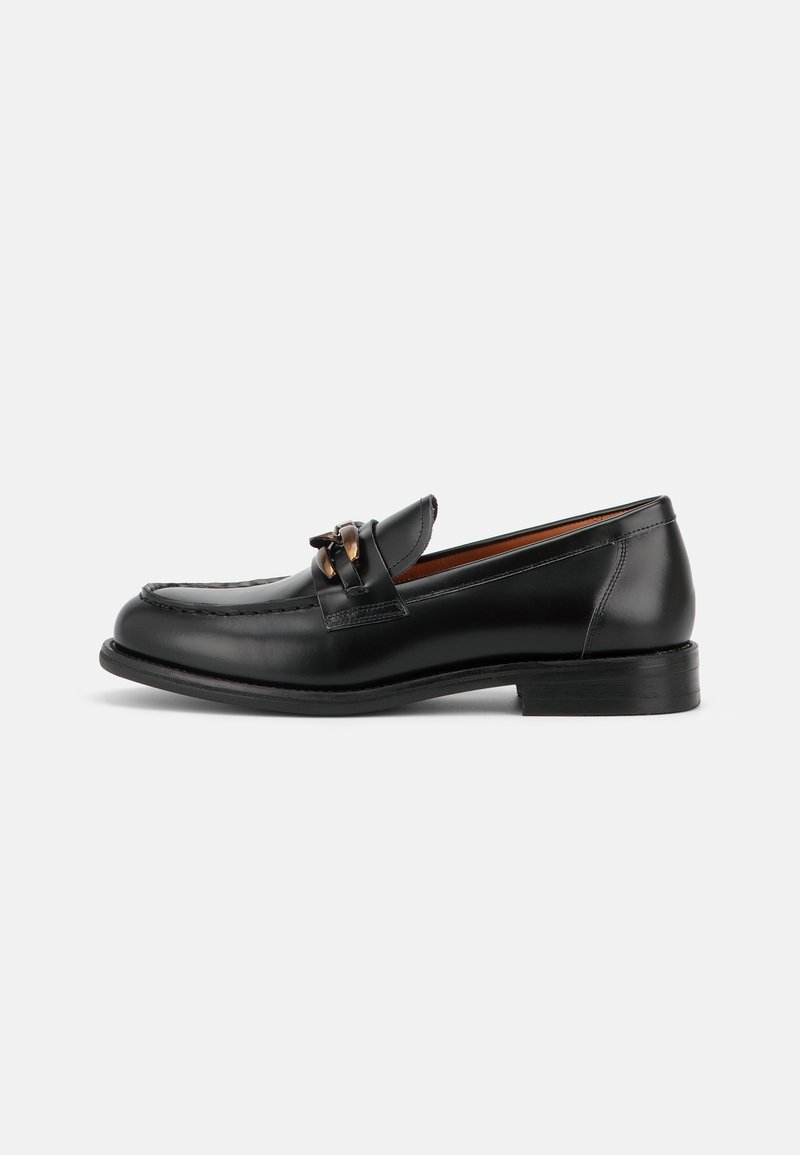 Mocassin en cuir noir avec un petit talon, un bout arrondi et un détail de boucle métallique décorative à l'avant.