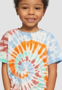 Koszulka t-shirt w stylu tie-dye z okrągłymi wzorami w kolorach pomarańczowym, turkusowym, niebieskim i brązowym na białym tle. Krótkie rękawy, wykonana z bawełny.