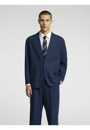 Costume bleu marine avec un revers cranté, un bouton unique et deux poches avant. Assorti à une chemise blanche et une cravate rayée. Conception sur mesure.