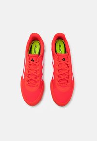 Czerwone buty sportowe z siateczkową cholewką, białymi paskami i amortyzowaną podeszwą. Wnętrze z jaskrawą zieloną marką. Sznurowany design, lekkie.
