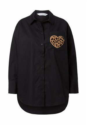 Zwart overhemd met knopen, een afgeronde zoom en lange mouwen. Heeft een hartvormige patch met luipaardprint op de linker borstzak.