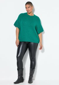 Teal oversized strikket sweater med korte ærmer, parret med elegante sorte faux læder leggings og sorte cowboy støvler.