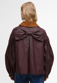 Βουργουνδία σακάκι με καφέ χοντρή κολάρο, φουσκωτά μανίκια και μεγάλη λεπτομέρεια φιόγκος στο πίσω μέρος. Απαλή υφή, τετραγωνισμένο σχήμα.