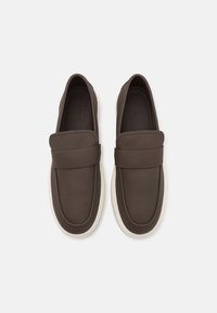 Hnědé kožené slip-on boty s kulatou špičkou, texturovaným svrškem a bílou gumovou podrážkou. Mají široký pásek přes nárt.