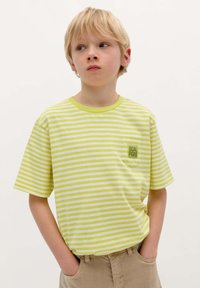 Groen en wit gestreepte T-shirt met een ronde halslijn, korte mouwen en een borstzak met de tekst "SCALPERS."