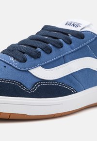 Baskets en daim bleu avec des accents blancs. Elles présentent une surface texturée, des lacets ronds et une semelle en caoutchouc avec un dessous en gomme. Logo sur la languette.