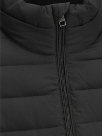 Giacca nera isolante con colletto alto, tessuto liscio e zip a lunghezza completa. Texture trapuntata con dettagli di cucitura orizzontale.