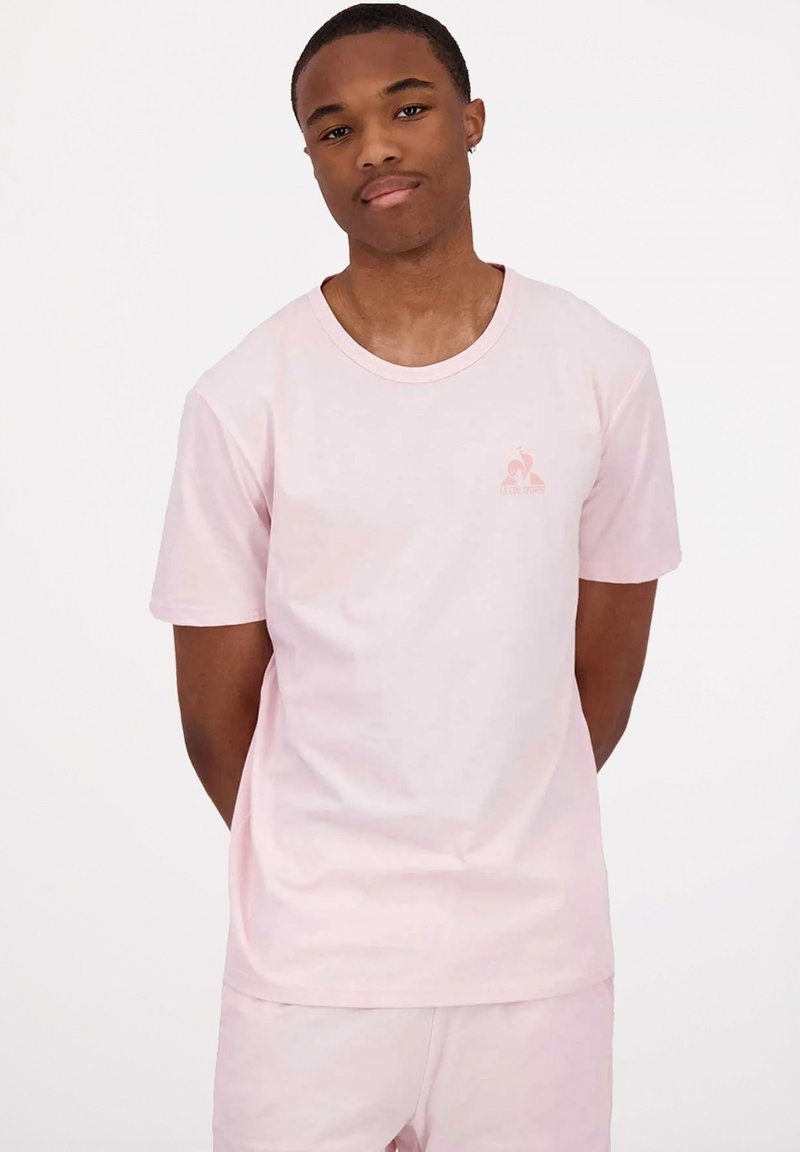 T-shirt in cotone rosa chiaro con scollatura rotonda e maniche corte. Presenta un piccolo logo sul petto e una vestibilità rilassata. Texture liscia.