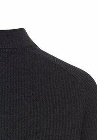 Schwarzer gerippter Strickstoff, der die Schulter und den Stehkragen eines Pullovers oder Sweatshirts zeigt.