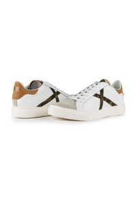 Sneakers in pelle bianca con accenti verde oliva e un tallone tan. Presentano lacci rotondi e una suola in gomma testurizzata.