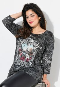 Schwarzes Langarm-T-Shirt mit Schädel- und Blumen-Grafikdruck, mit lockerer Passform und leicht abgerundetem Ausschnitt. Texturiertes Stoffdesign.
