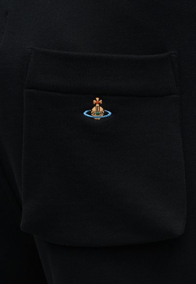 Μαύρο υλικό φλις με τσέπη πατς που φέρει κεντητό σχέδιο σκάφους περιβαλλόμενο από μπλε κύκλο. Ορατή υφή υφάσματος.