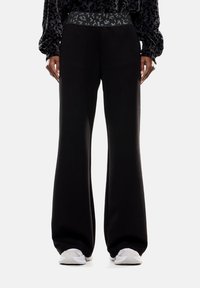 Pantaloni larghi neri in felpa con una cintura testurizzata caratterizzata da un motivo sottile. Materiale liscio con una vestibilità comoda, adatti per un abbigliamento casual.