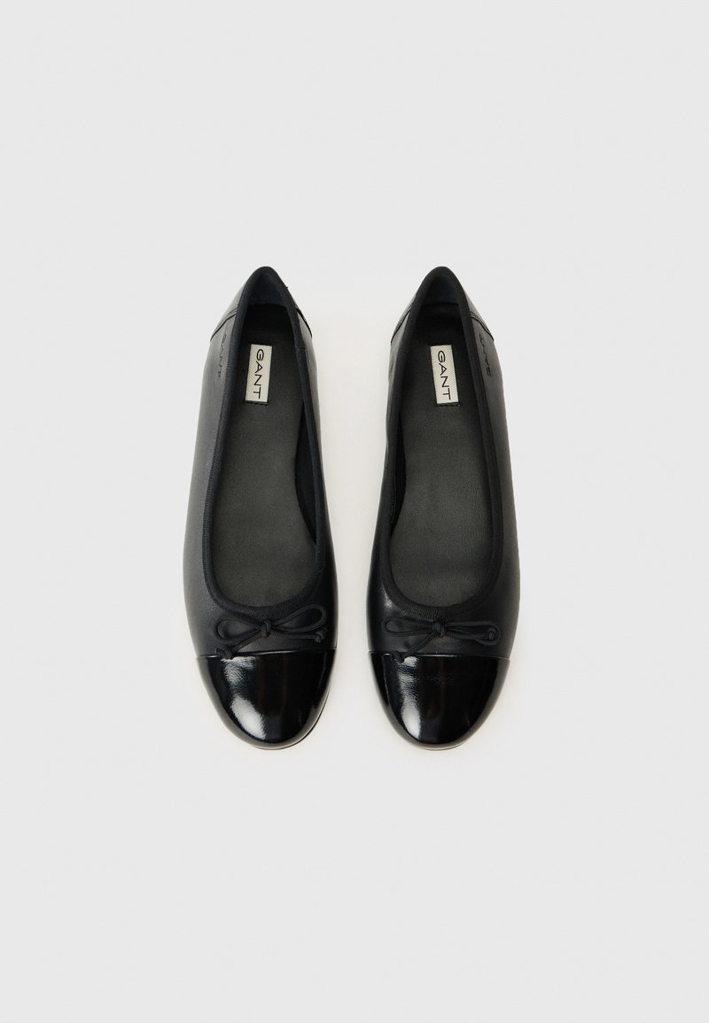 Ballerines noires en cuir, dotées d'un bout rond avec un cap brillant, d'un petit nœud sur le devant et d'une doublure intérieure lisse.