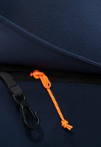 Granatowy materiał o teksturowanej powierzchni; posiada czarny zamek błyskawiczny oraz pomarańczowy sznurek z odblaskowymi detalami. W zestawie czarna zawieszka na hak.