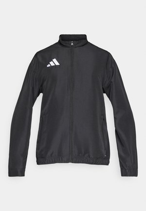 Μαύρο μπουφάν με φερμουάρ, κατασκευασμένο από λείο ύφασμα. Διαθέτει ψηλό γιακά, ελαστικά μανίκια και λευκό λογότυπο στον αριστερό ώμο.