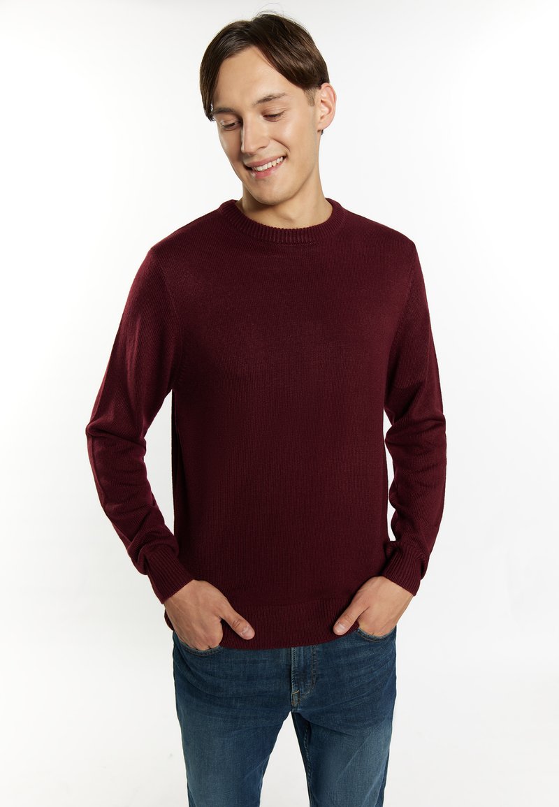 Maglione girocollo bordeaux realizzato in tessuto a maglia testurizzato, con maniche lunghe e polsini a coste, abbinato a jeans blu.