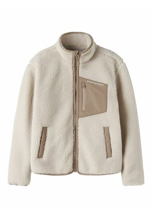 Veste polaire beige avec fermeture éclair intégrale à l'avant, deux poches latérales et une poche poitrine étiquetée "STUDIO OUTDOORS" en tissu contrastant.
