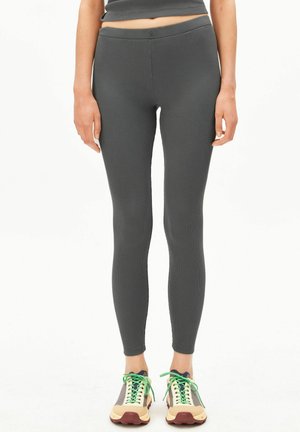 Dunkelgraue, gerippte Leggings mit enger Passform, elastischem Bund und glatter Textur, kombiniert mit bunten Sportschuhen.