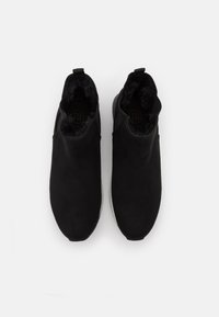 Černé kotníkové boty z semiše s měkkou kožešinovou podšívkou, které mají minimalistický design a elastické boční panely pro snadné obouvání.