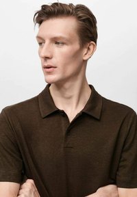 Tmavohnědá polo tričko s klasickým límcem, knoflíkovou légou a krátkými rukávy. Tkanina vypadá strukturovaně, vhodné pro volnočasové nošení.