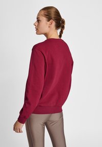 Bordeaux sweatshirt met een ronde halslijn, geribde manchetten en zoom. De stof is zacht, glad en heeft een relaxte pasvorm. Opmerking: achterkant weergegeven.
