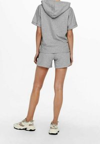 Grå bomullshoodie med korta ärmar, parat med matchande shorts. Har en huva och avslappnad passform. Bärs med beige och vita sportskor.