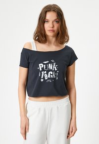 Zwarte cropped t-shirt met een off-shoulder ontwerp, voorzien van een witte grafische druk met de tekst "PUNK ROCK." Zacht materiaal en een relaxed fit.