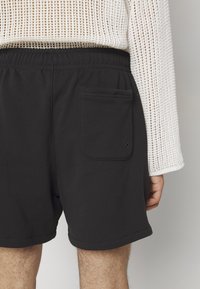 Svarta shorts i en bomullsblandning, med ett elastiskt midjeband, sidoficka och en enkel, slät textur.