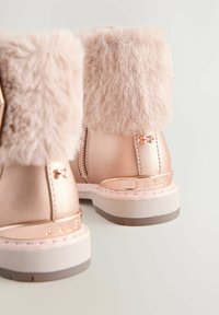 Botines metálicos rosas con ribete de piel sintética, cremalleras y un lazo decorativo. Presentan una suela blanca resistente con un acento gris.
